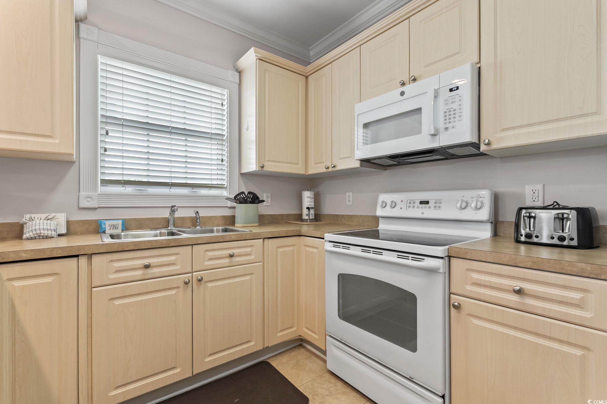 4821 Luster Leaf Circle, Unit 105 Myrtle Beach, SC 29577 - Photo 5 of 40 Kitchen with white appliances, light countertops, crown molding, and light tile patterned flooring