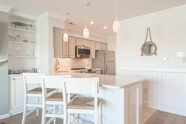 a kitchen with stainless steel appliances a stove a sink refrigerator and white cabinets with wooden floor