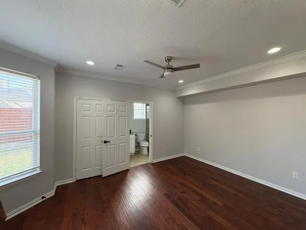 a view of an empty room with a window and wooden floor
