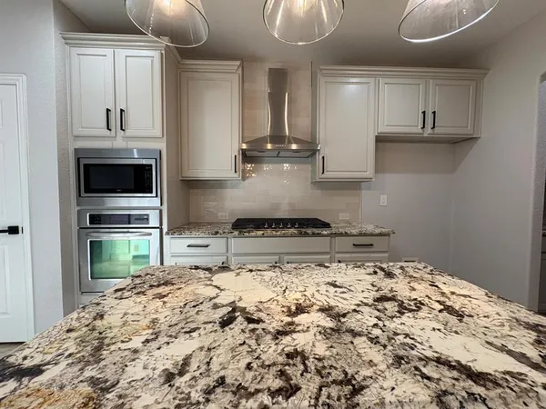 a kitchen with stainless steel appliances granite countertop a stove a sink and a refrigerator