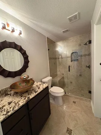 a bathroom with a granite countertop sink toilet a mirror and shower