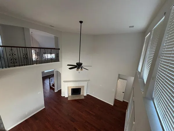 a view of an empty room with wooden floor fireplace and a window