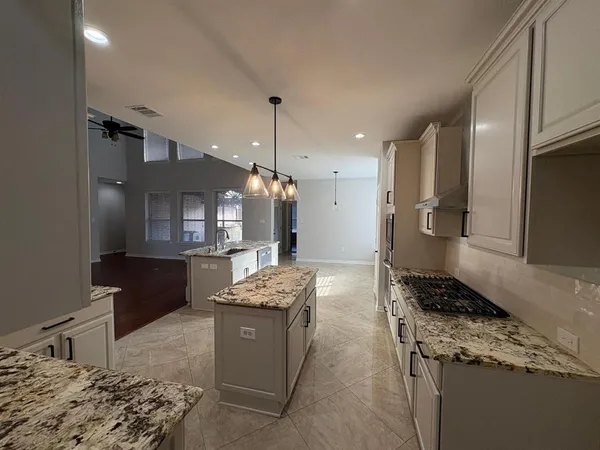 a kitchen with stainless steel appliances kitchen island granite countertop a stove a sink a refrigerator and a cabinets