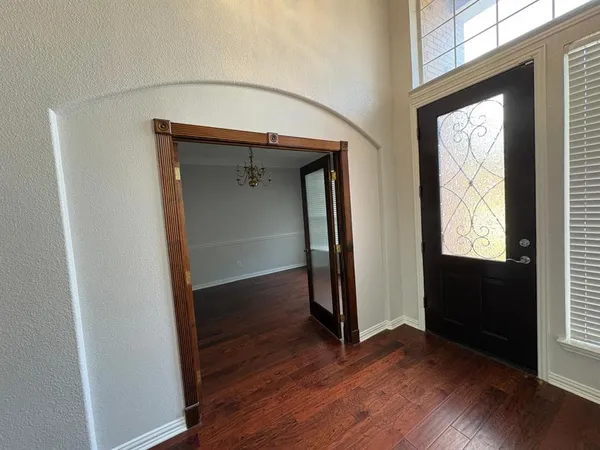 an empty room with wooden floor closet and windows