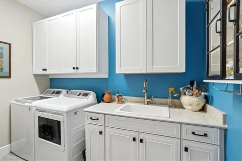 a utility room with stainless steel appliances white cabinets and a sink