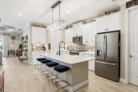a kitchen with stainless steel appliances a dining table a sink a stove a refrigerator and chairs