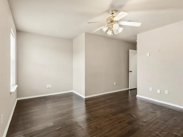 an empty room with wooden floor and chandelier fan