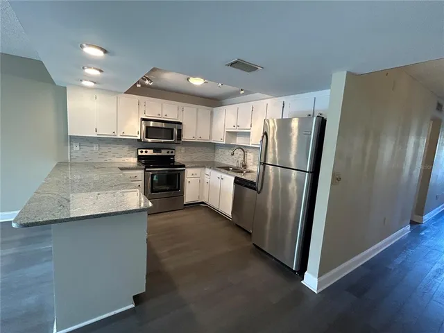 a kitchen with stainless steel appliances granite countertop a refrigerator a stove a sink and a microwave