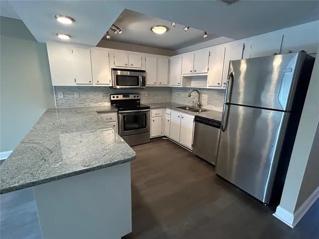 a kitchen with granite countertop stainless steel appliances and wooden cabinets