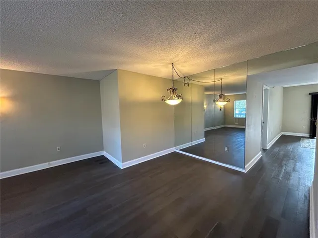 an empty room with wooden floor and mirror