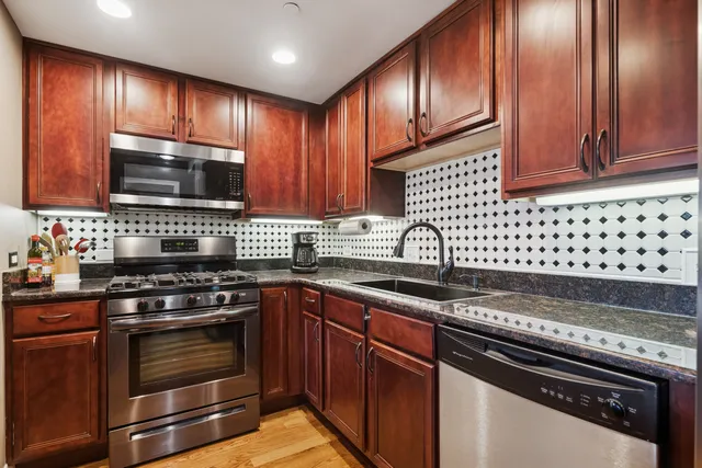 a kitchen with granite countertop cabinets stainless steel appliances and wooden cabinets