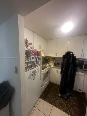 a kitchen with a refrigerator and white cabinets