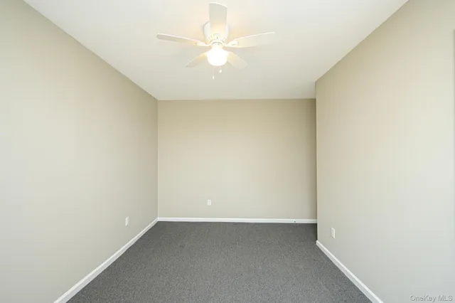 an empty room with a ceiling fan and a window