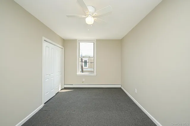 an empty room with a window and a ceiling fan