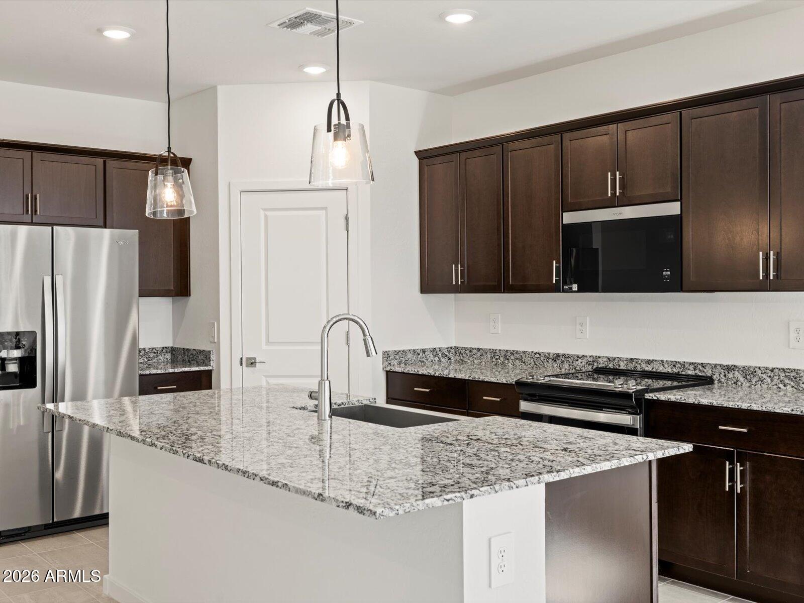 a kitchen with stainless steel appliances granite countertop a sink refrigerator and microwave