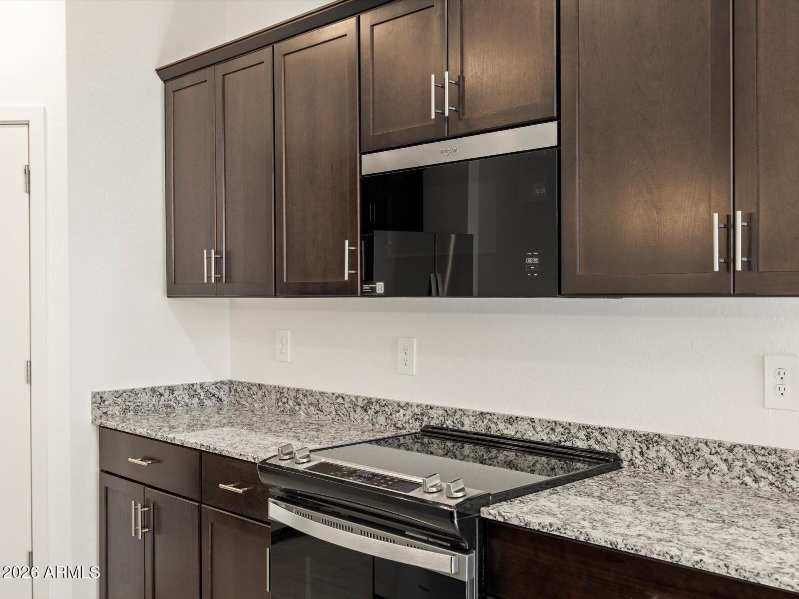 8936 South 244th Lane Buckeye, AZ 85326 - Photo 41 of 45 a kitchen with granite countertop cabinets and black appliances