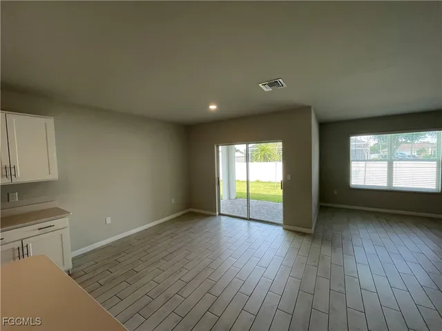 a view of an empty room with a window and wooden floor
