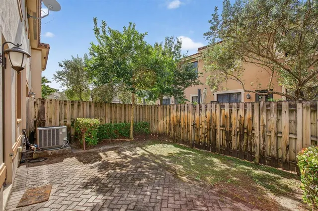 a view of a backyard with large trees and wooden fence
