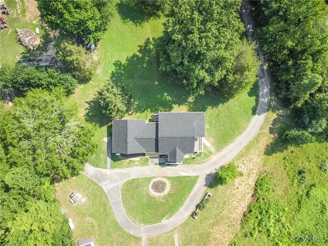 an aerial view of a house with garden space and trees in the back