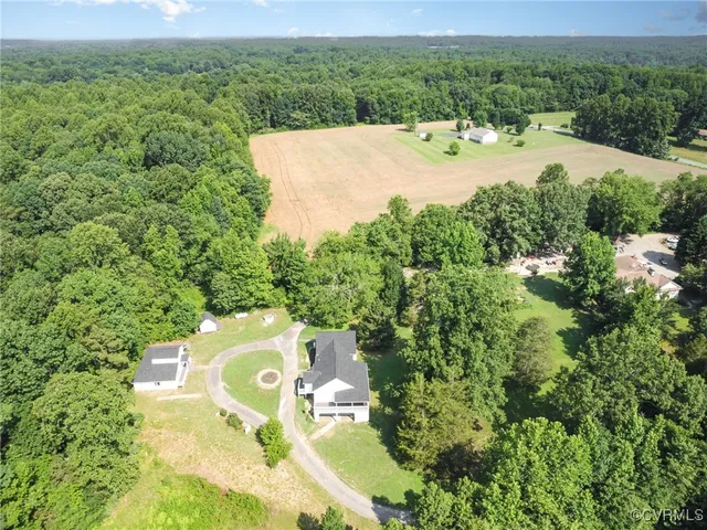 an aerial view of residential house with outdoor space and trees all around