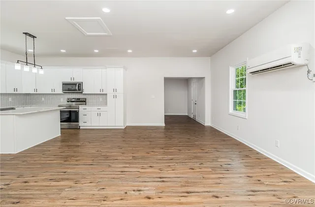 a view of kitchen with kitchen island a sink wooden floor and stainless steel appliances