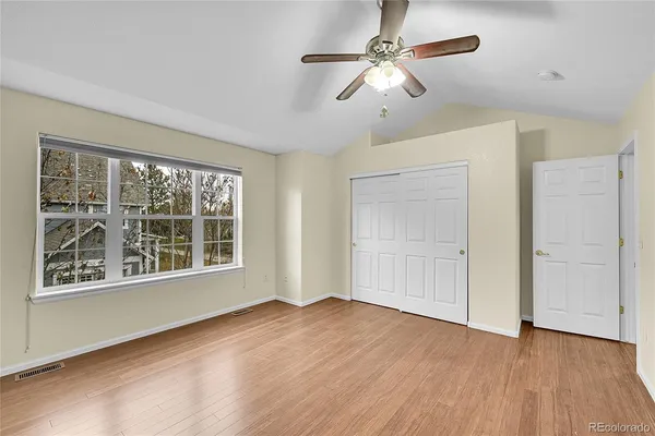 a view of an empty room with a window and wooden floor
