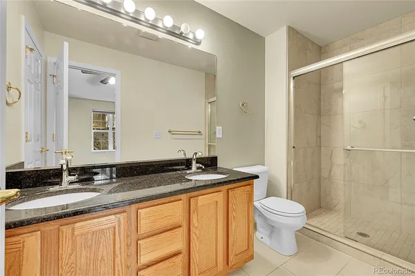 a bathroom with a granite countertop sink a toilet a mirror and shower