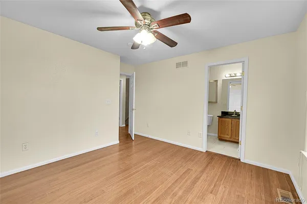 an empty room with wooden floor and a ceiling fan