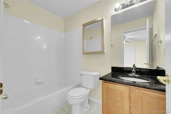 a bathroom with a granite countertop sink a toilet a mirror and bathtub
