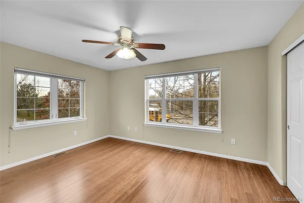 a view of an empty room with wooden floor and a window