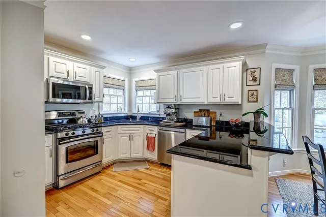 a kitchen with granite countertop a stove top oven a sink dishwasher a dining table and chairs with wooden floor