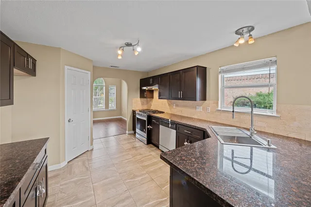 a kitchen with stainless steel appliances granite countertop a sink stove and cabinets