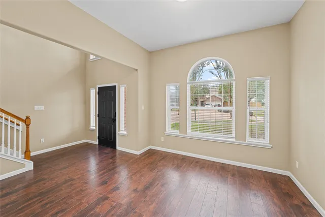 a view of an empty room with a window and wooden floor