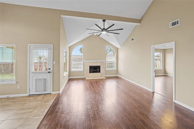 an empty room with wooden floor fireplace and windows