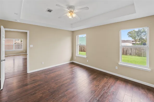 a view of an empty room with window and wooden floor