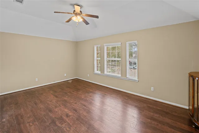 a view of an empty room with window and wooden floor