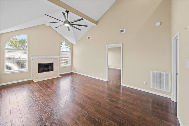 an empty room with wooden floor fireplace and windows