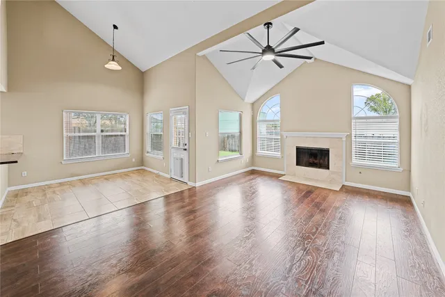 an empty room with wooden floor fireplace and windows