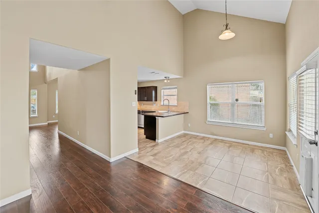 an empty room with wooden floor cabinet and windows
