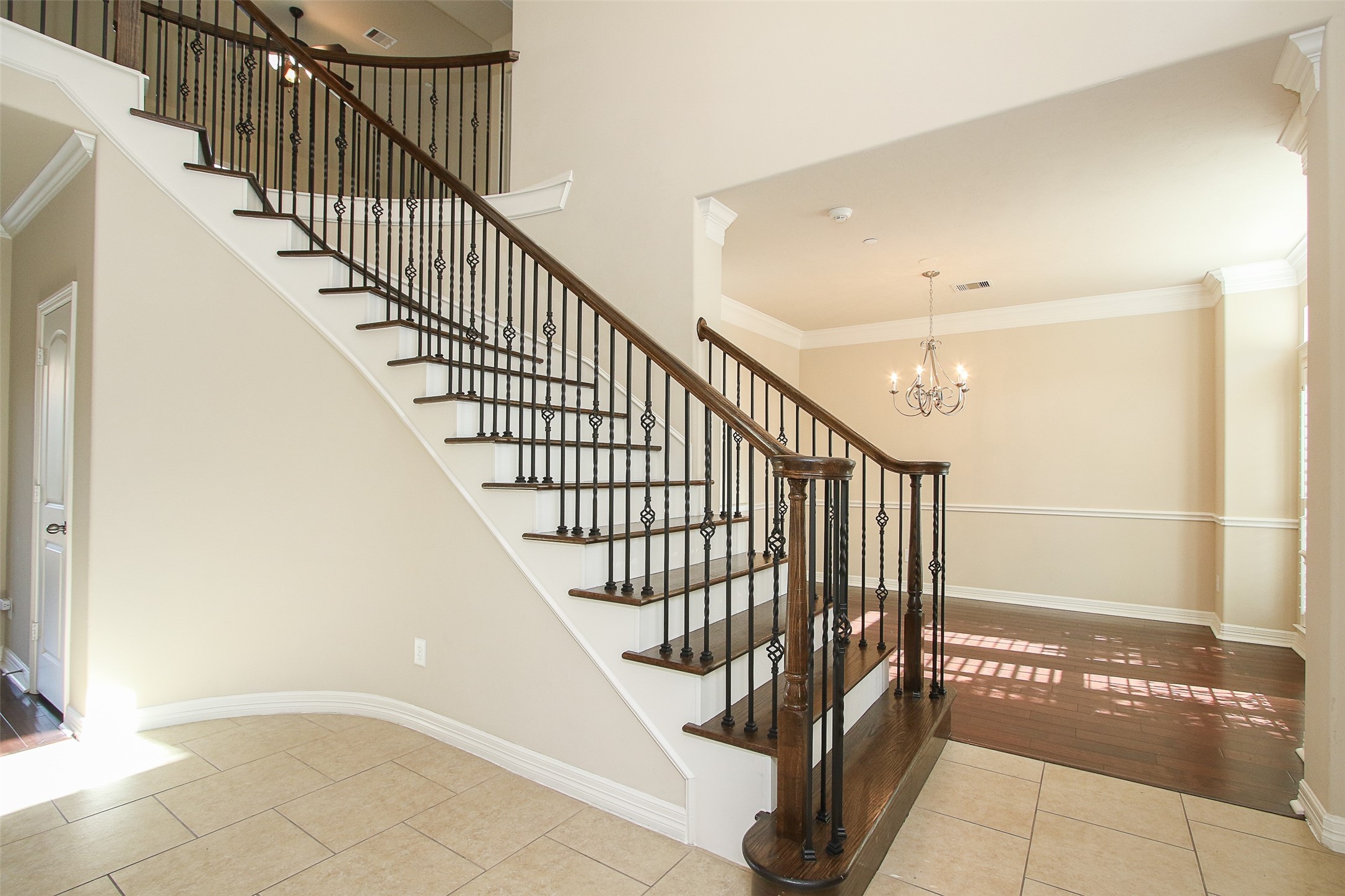 11722 Spriggs Way Houston, TX 77024 - Photo 7 of 49 Beautiful wrought iron staircase at the front of the home leads upstairs to the game room. Dining room with pretty chandelier and wood flooring straight ahead.