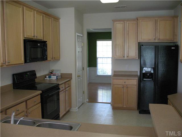 7409 Brandon Allen Avenue Raleigh, NC 27613 - Photo 5 of 14 Kitchen with stain cabinets, custom color countertops, smooth surface range, microwave and refrigerator.