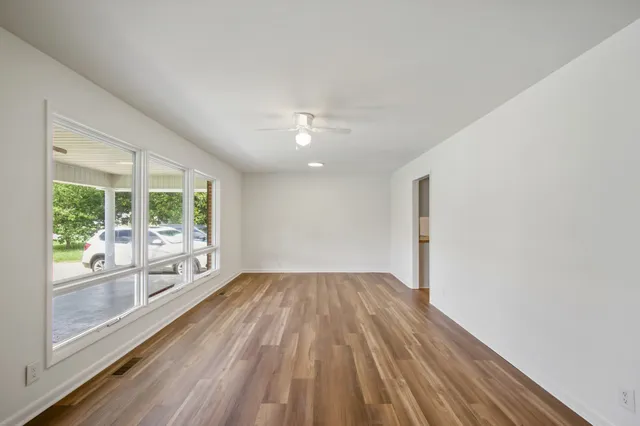 an empty room with wooden floor and windows