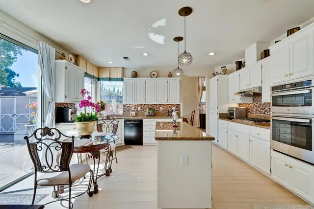 a kitchen with granite countertop white cabinets and stainless steel appliances