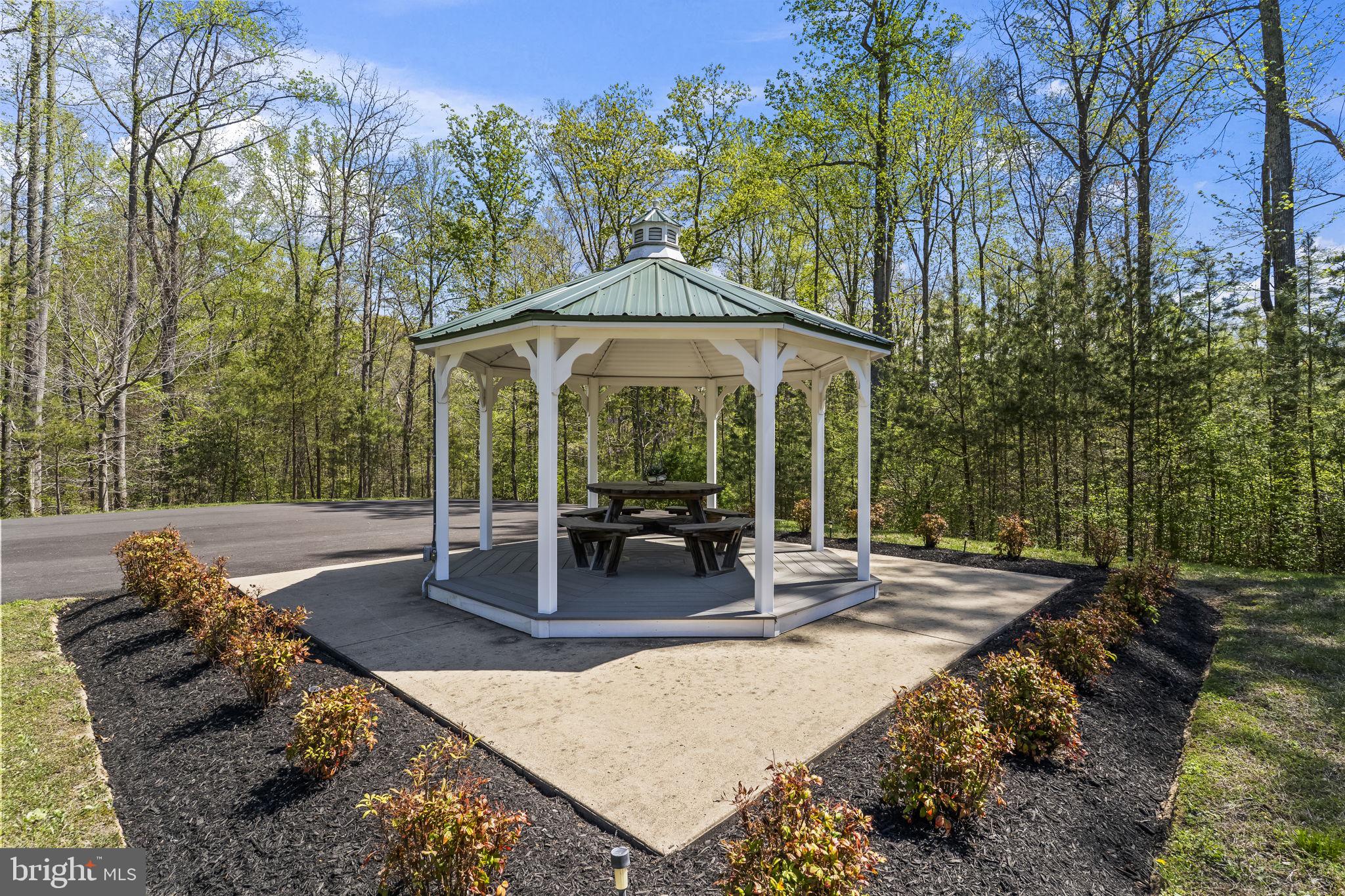 1905 Resting Ridge Lane Prince Frederick, MD 20678 - Photo 75 of 91 a view of a patio with table and chairs under an umbrella with large trees