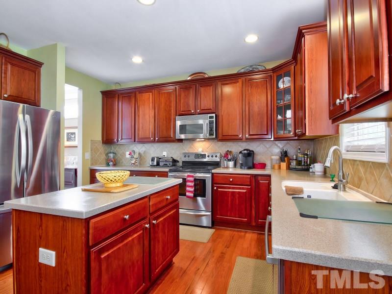 5304 Jade Forest Trail Raleigh, NC 27616 - Photo 7 of 22 a kitchen with stainless steel appliances granite countertop wooden cabinets a stove top oven a sink and dishwasher a oven with wooden floor