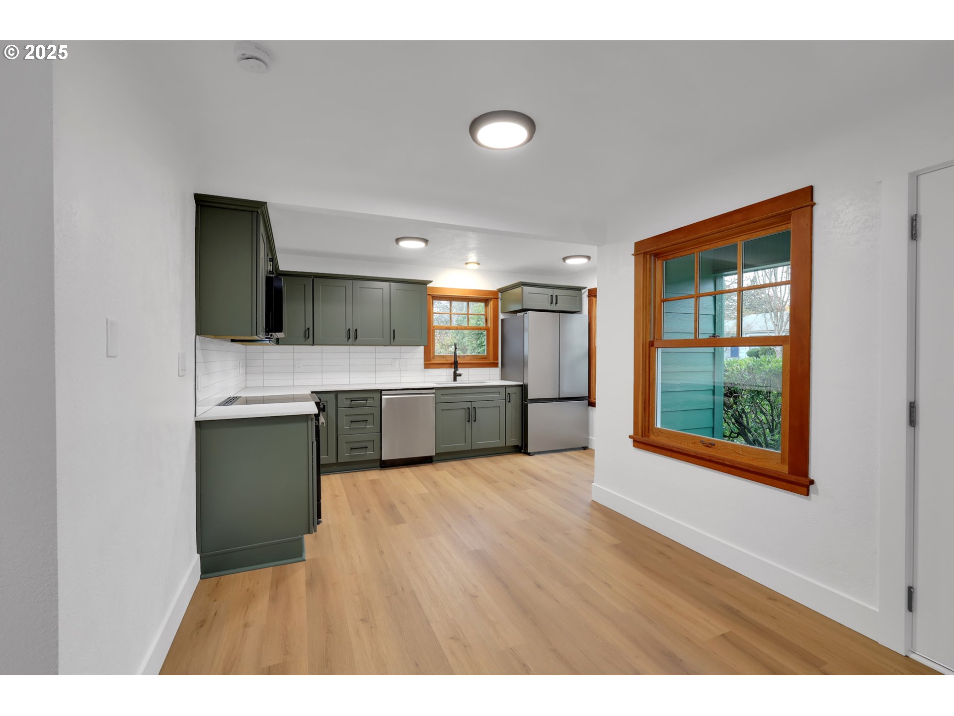 2121 Jefferson Street Eugene, OR 97405 - Photo 9 of 35 a open kitchen with kitchen island a sink dishwasher a stove with wooden floor and a large window