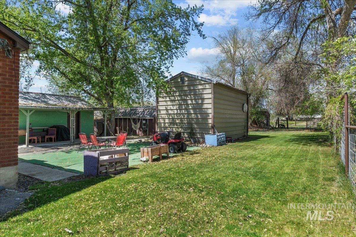 1958 East 1775 South Gooding, ID 83330 - Photo 49 of 49 Expansive green lawn area featuring a metal utility shed, mature trees, and a covered patio with artificial turf