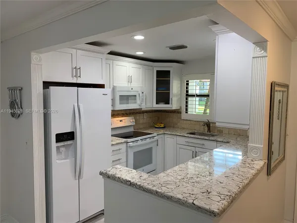 a kitchen with granite countertop a sink stove and refrigerator