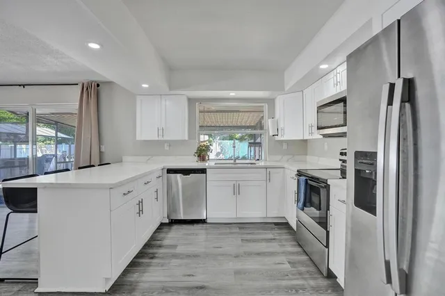 a kitchen with granite countertop white cabinets and white stainless steel appliances