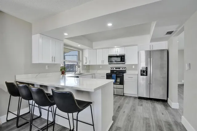 a kitchen with kitchen island white cabinets and stainless steel appliances